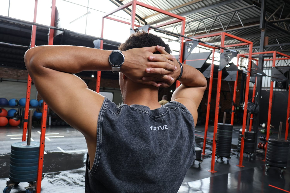 Person in a gym wearing a 'Virtue' shirt with workout equipment in the background